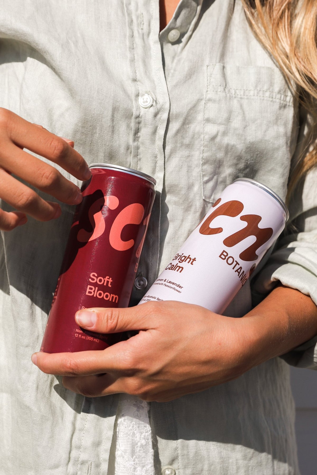 Soft Bloom and Bright Calm cans held against a linen shirt